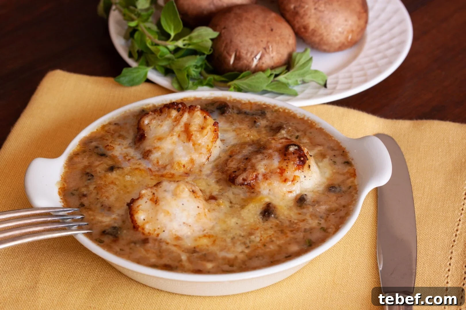 Coquilles St. Jacques Coquilles St. Jacques in a white plate with fork and knife next to it ready to be enjoyed