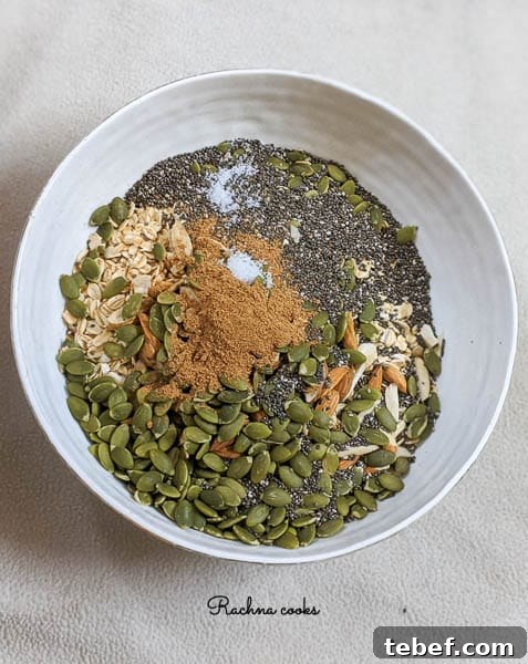 Crunchy Air Fryer Granola Recipe for Perfect Homemade Clusters 6 rolled oats, pepitas, chia seeds, pumpkin spice, slivered almonds in a white bowl.
