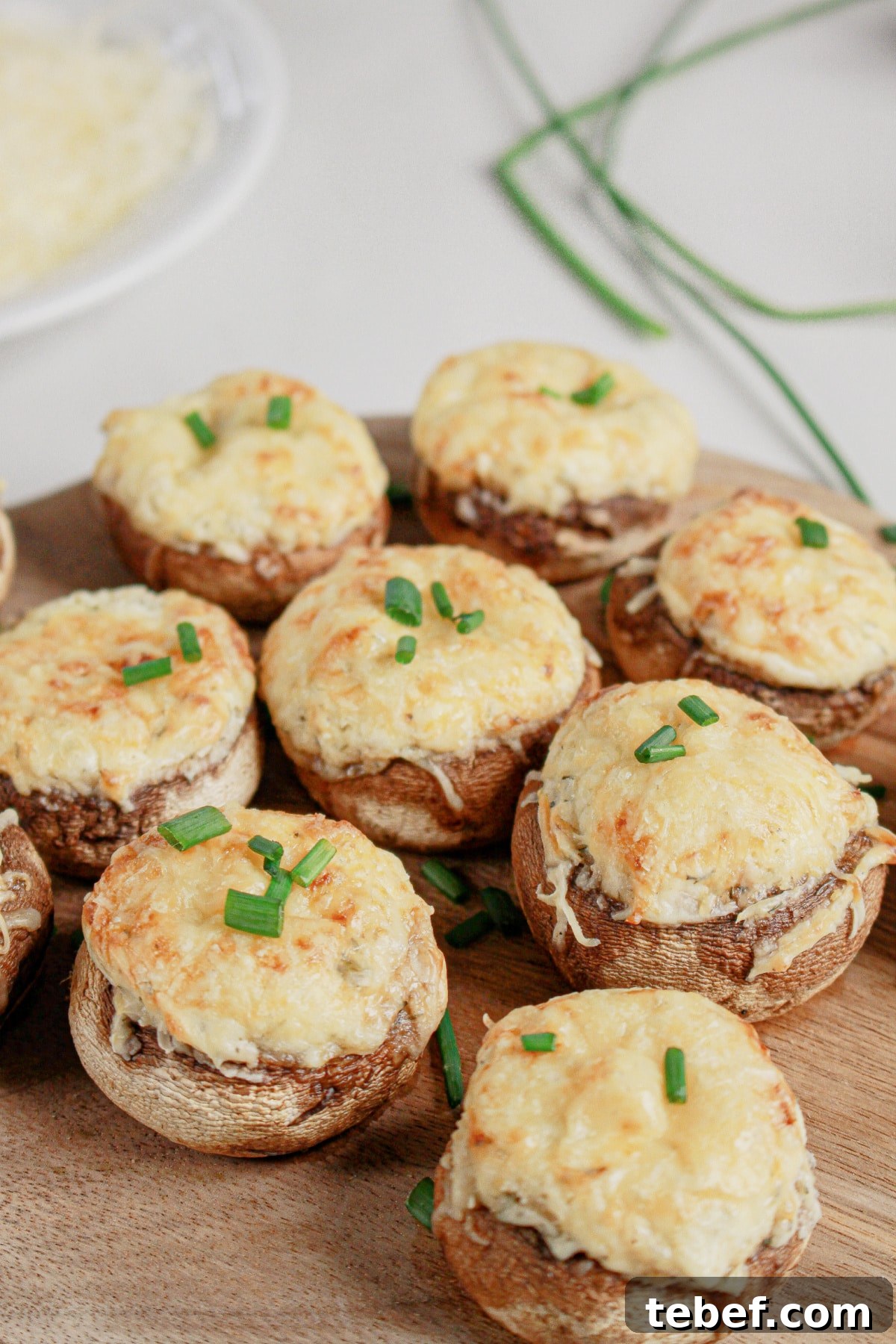 Cream Cheese Stuffed Mushrooms Recipe with Garlic and Herbs 2 Cream cheese stuffed mushrooms on a wooden cutting board.