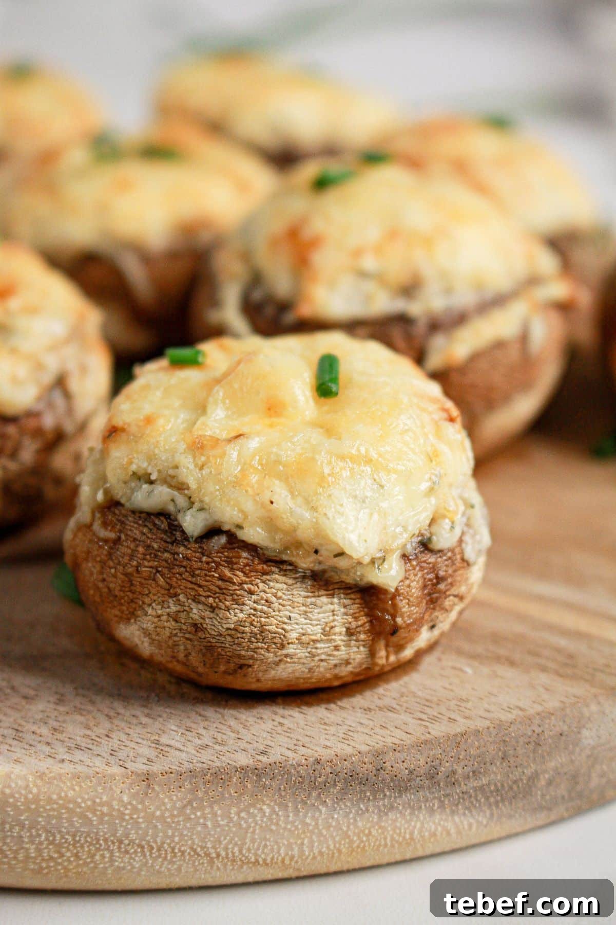 Cream Cheese Stuffed Mushrooms Recipe with Garlic and Herbs 3 Cream cheese stuffed mushrooms on a wooden cutting board.