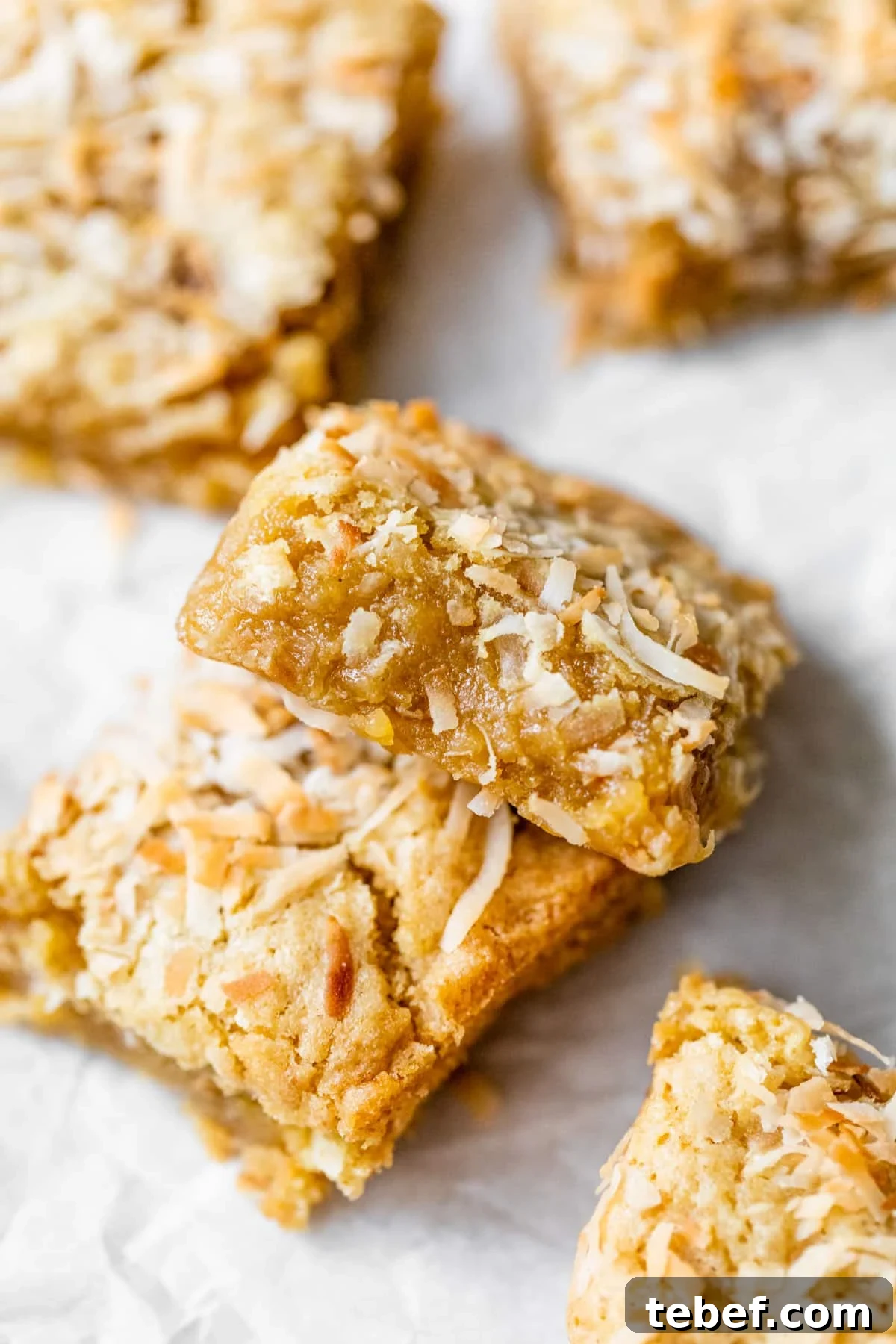 Buttery Coconut Bars Recipe with Crisp Shortbread Crust 2 buttery bars with coconut on parchment paper