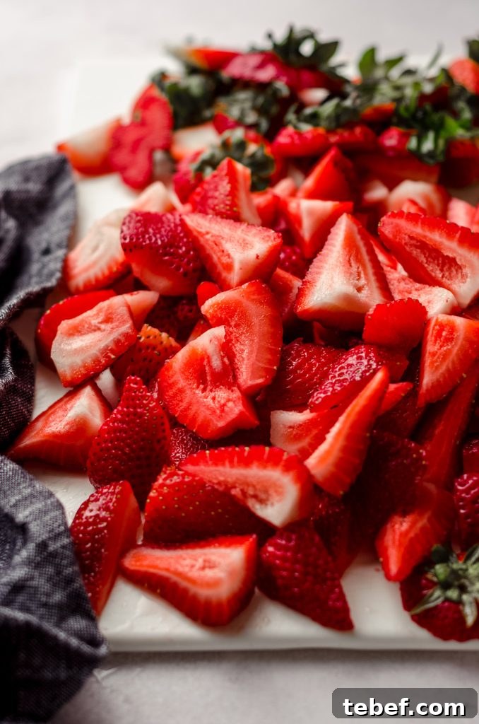 Decadent Strawberry Swiss Roll Recipe with Cream Filling 13 strawberries sliced on a cutting board