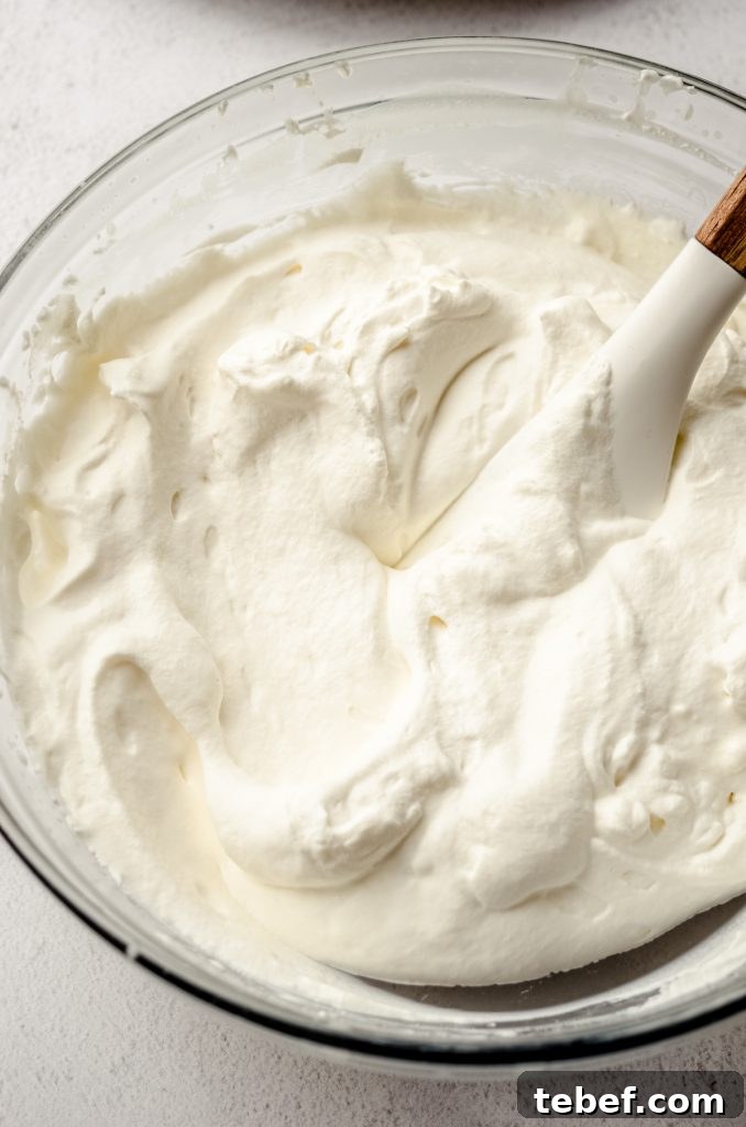 A large bowl of whipped cream with a spatula in it.