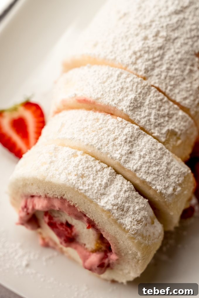 Decadent Strawberry Swiss Roll Recipe with Cream Filling 18 A strawberry Swiss roll cake on a plate with strawberries around it.