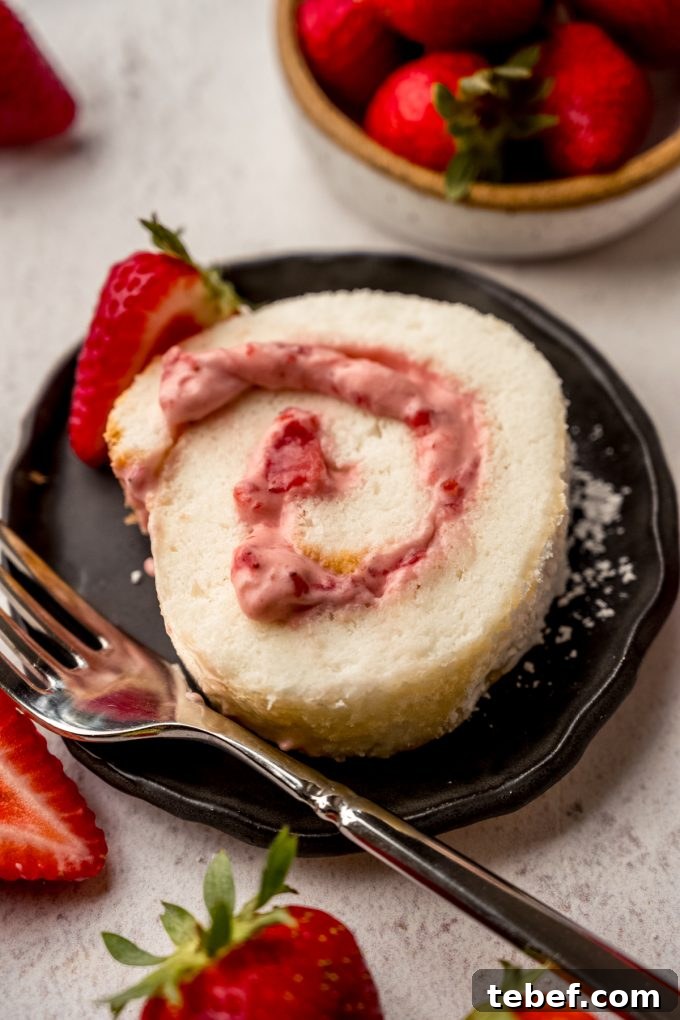 Decadent Strawberry Swiss Roll Recipe with Cream Filling 20 A slice of strawberry Swiss roll cake on a plate with a fork.
