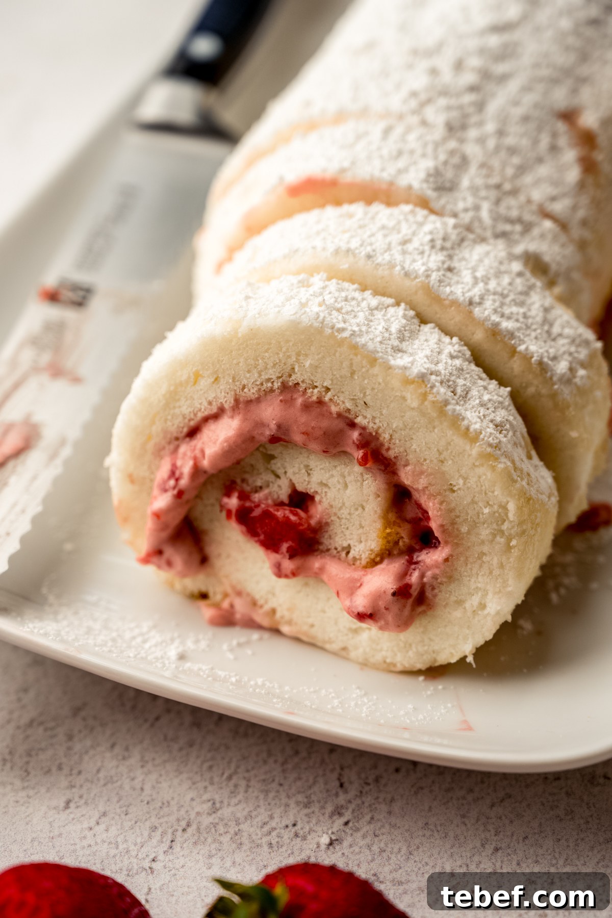 Decadent Strawberry Swiss Roll Recipe with Cream Filling 6 A strawberry Swiss roll cake on a plate.