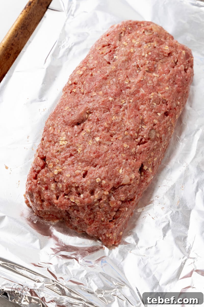 Bourbon-Glazed Bacon Meatloaf Recipe 3 The meat is folded into a loaf and placed on a tray lined with foil.