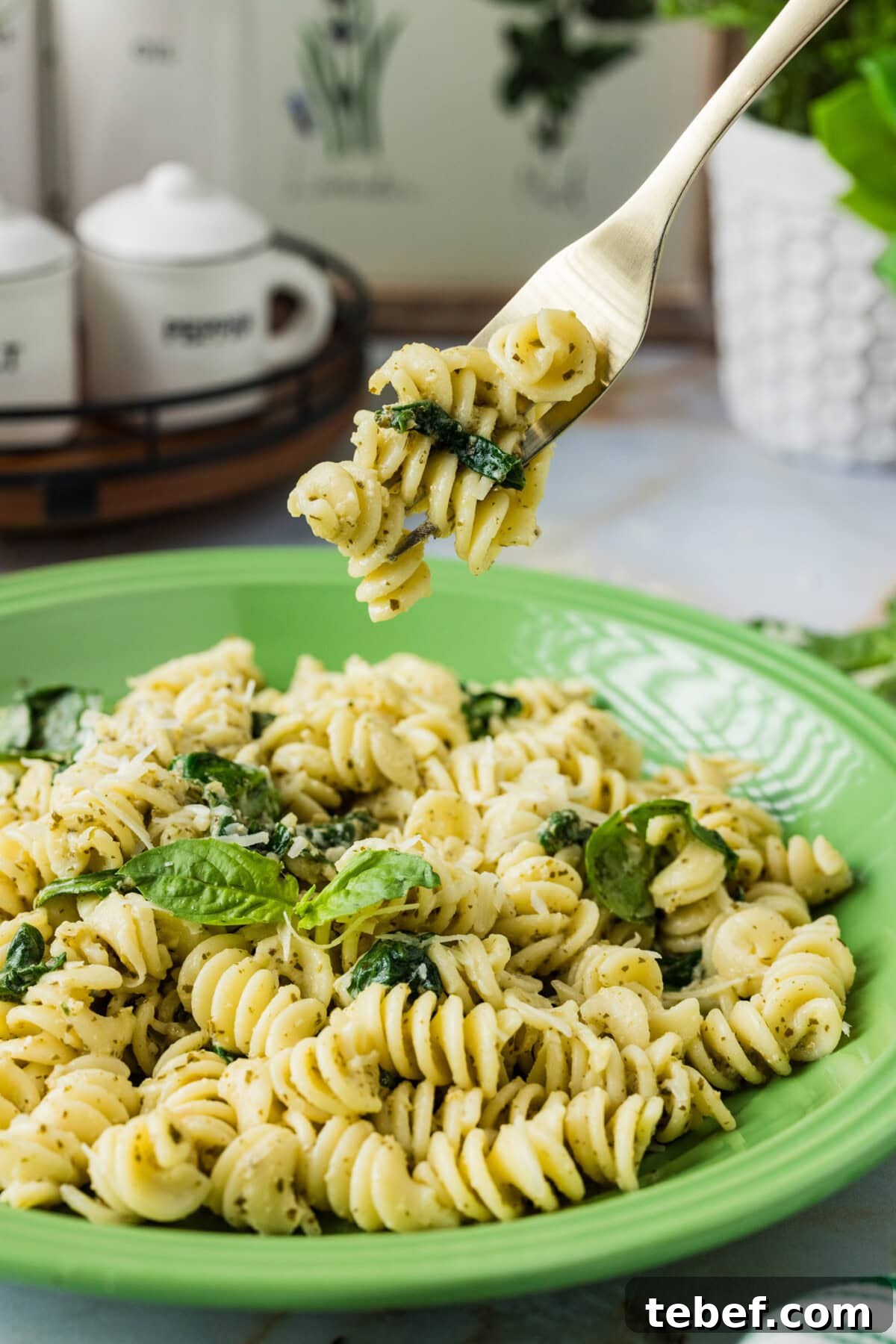 Creamy Basil Pesto Pasta with Parmesan and Pine Nuts 3 Forkful of Pesto Pasta held above a plate of Pesto Pasta