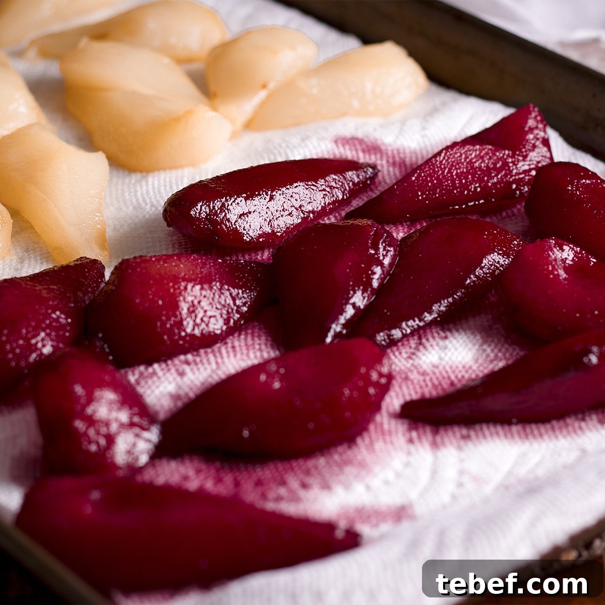Wine poach pears lying on paper towels to drain.