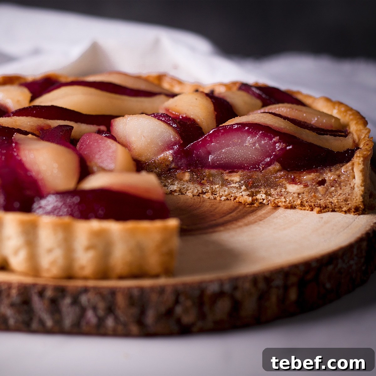 A poached pear and frangipane tart with a slice removed from it.
