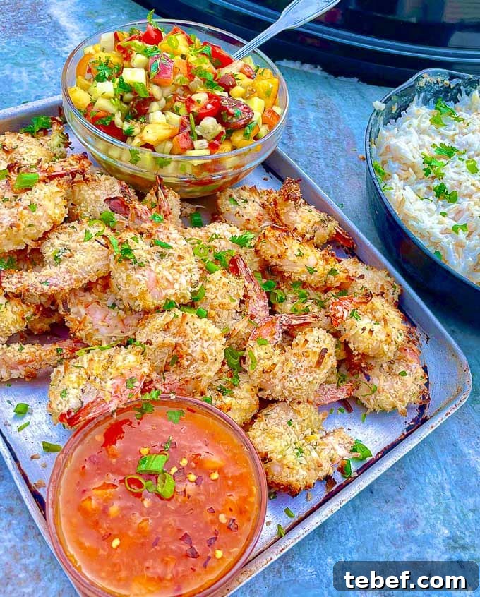 Crispy Grilled Coconut Shrimp with Peach Sauce and Coconut Sticky Rice on a baking sheet with peach tomato salad