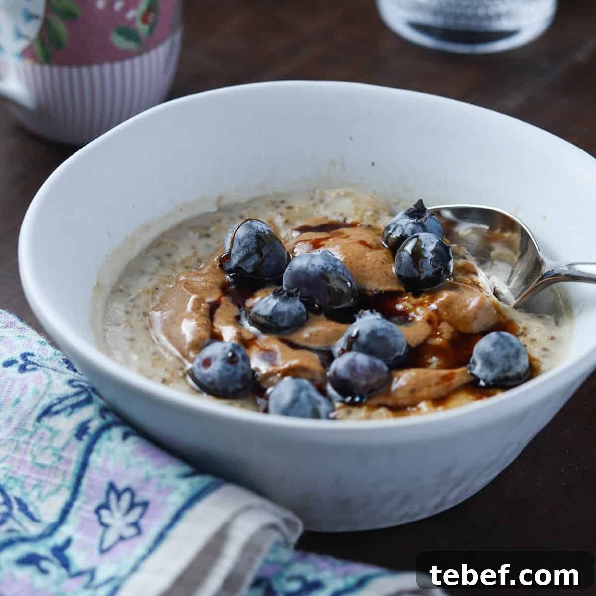 photo of a white bowl of vegan oat and chia seed porridge with blueberries and coconut almond butter on top
