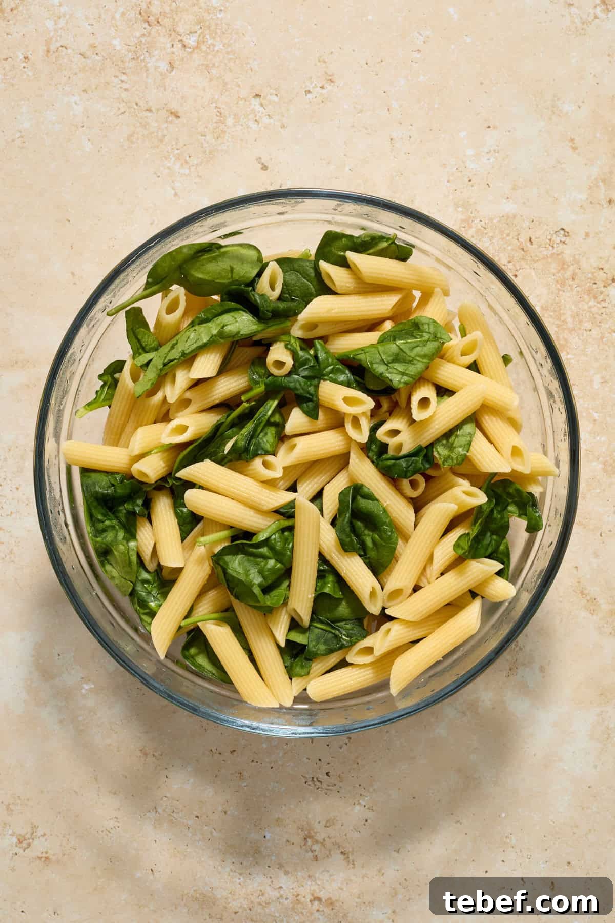 Sun-Dried Tomato Pasta with Savory Italian Sausage 6 Pasta in glass bowl with spinach.