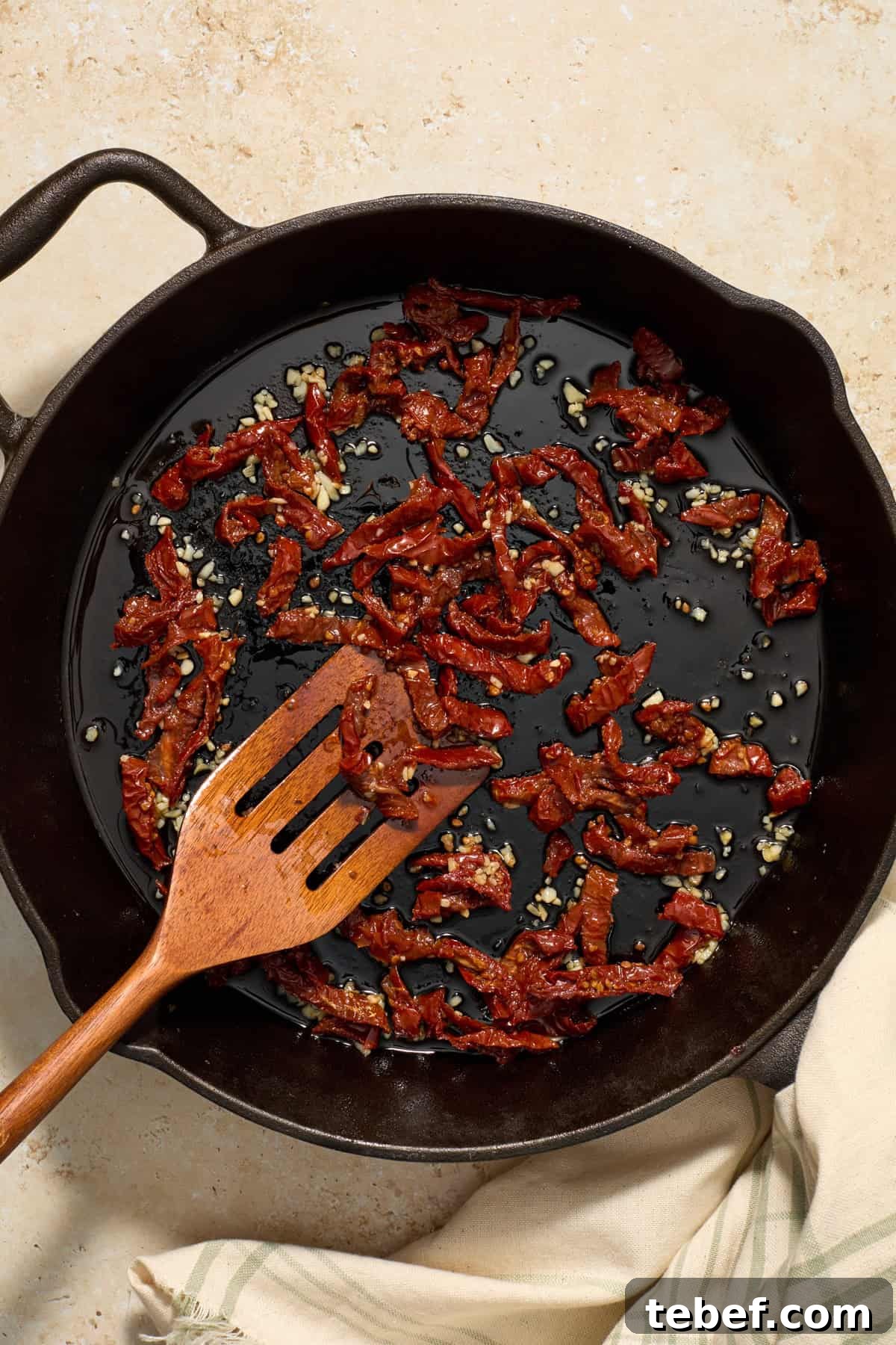 Sun-Dried Tomato Pasta with Savory Italian Sausage 7 Sun-dried tomatoes and garlic in skillet with wood slotted spoon.