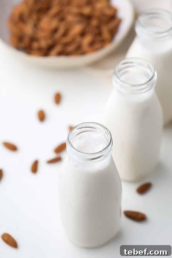 Almond Milk from Soaked Almonds: Quick Soak Method Guide 5 two glass milk bottles holding white almond milk, almonds in background