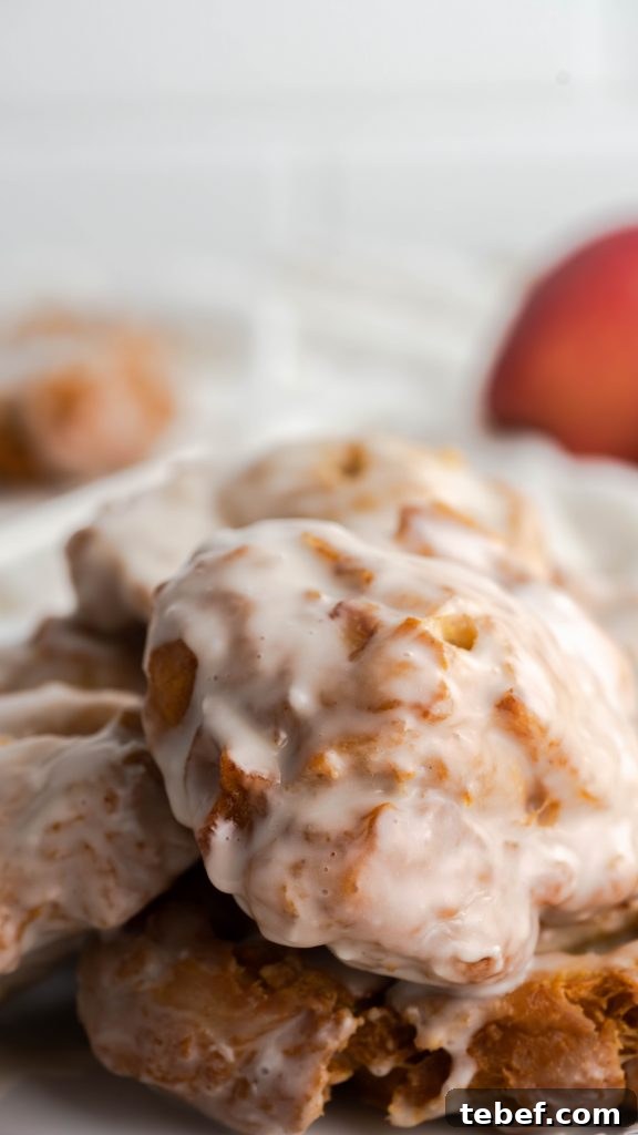 Crispy Homemade Apple Fritters Recipe for Irresistible Fall Treats 2 Glazed homemade apple fritters on white plate.
