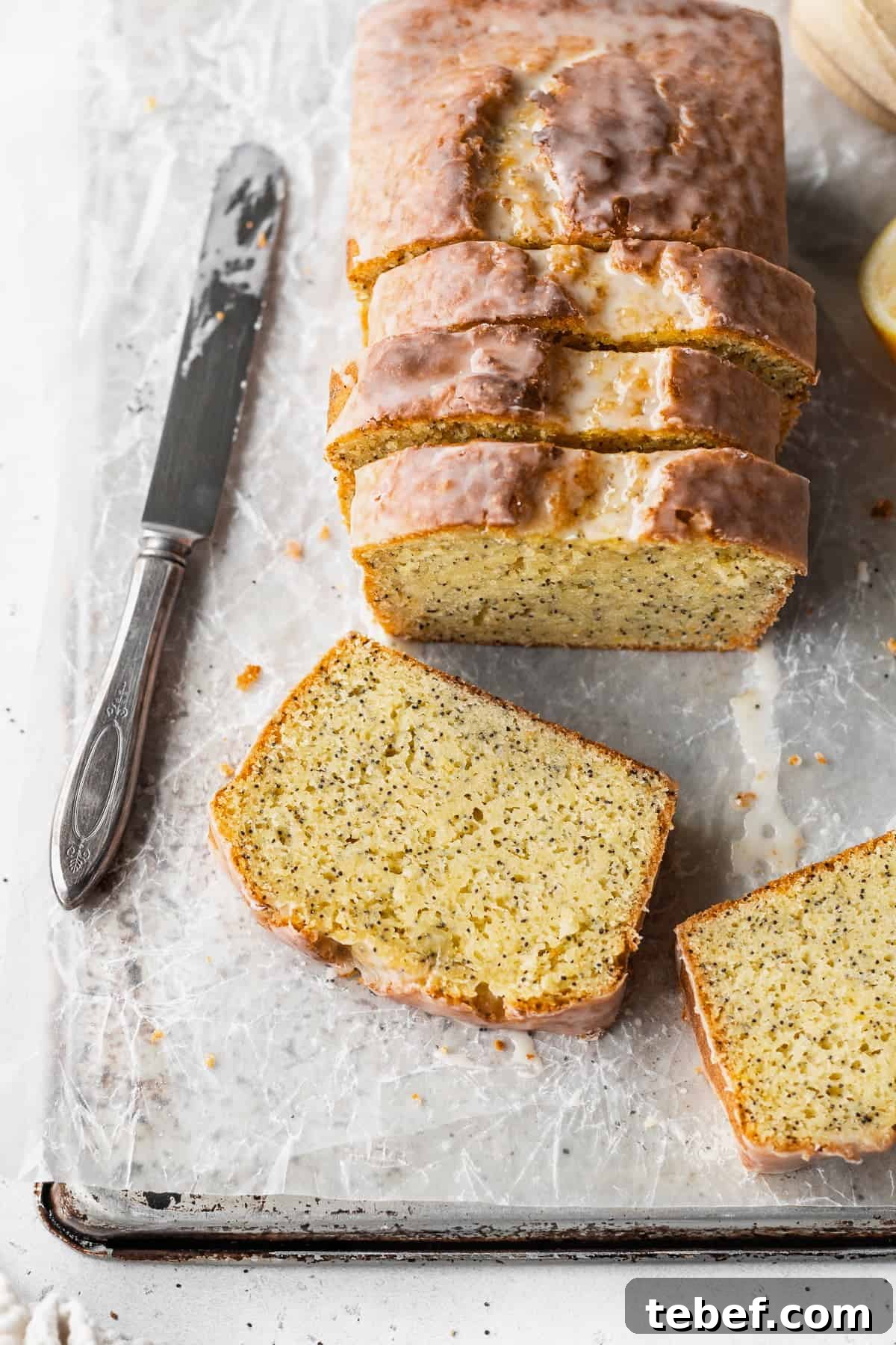 Overhead shot of a sliced lemon poppyseed loaf with two slices laying in front of it.