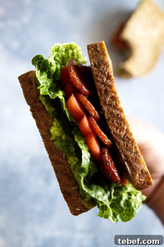 Crispy Tempeh BLT Sandwich — Vegan Bacon, Lettuce & Tomato 3 Hand Holding a Vegan BLT Sandwich