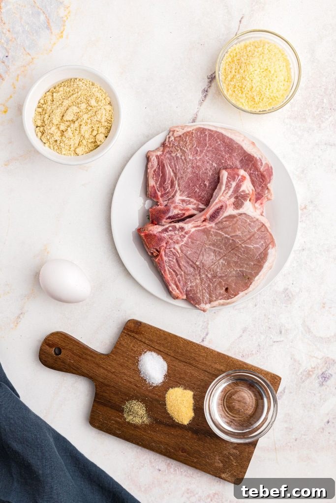 Crispy Gluten-Free Pork Chops in the Air Fryer 3 Ingredients measured on a marble table with pork chops in the center and a blue linen.