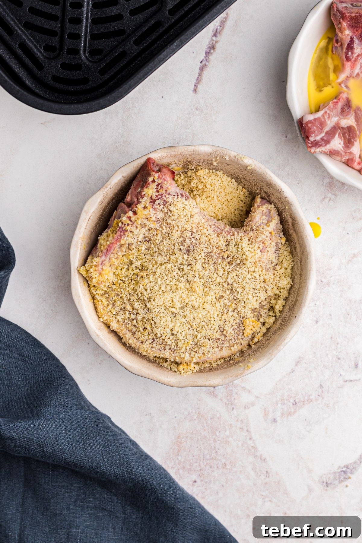 Crispy Gluten-Free Pork Chops in the Air Fryer 6 White shallow bowl with pork chop being coated with almond flour and parm cheese and seasonings.