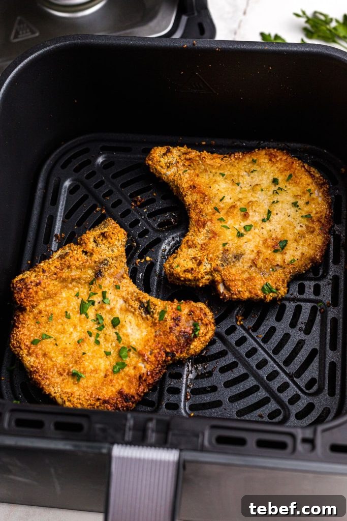 Crispy Gluten-Free Pork Chops in the Air Fryer 9 Golden coated pork chops in the air fryer basket and garnished with parsley flakes
