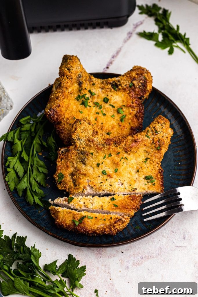 Crispy Gluten-Free Pork Chops in the Air Fryer 10 Golden crispy pork chops on a blue plate with a fork and parsley garnish
