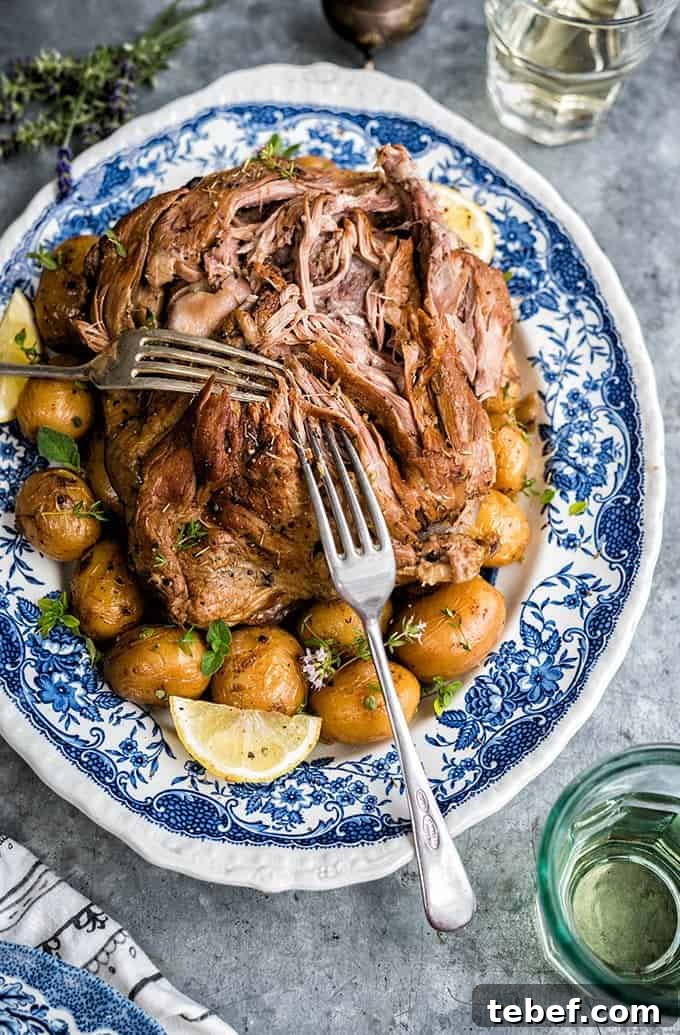 Platter of tender slow cooked Greek Lamb with two forks pulling apart