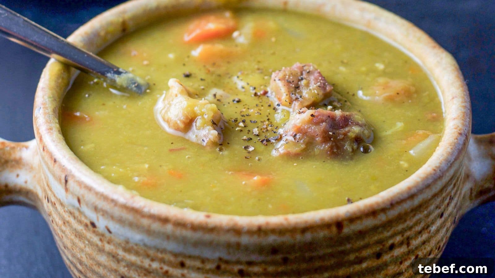 Instant Pot Split Pea Soup Recipe – Creamy, Hearty & Ready Fast 3 A crock with pea soup with ham in it, along with ground pepper and a spoon
