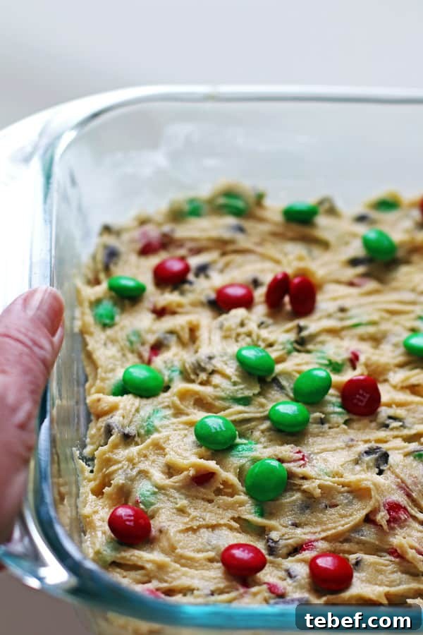 Chewy Cookie Bars Recipe: Gooey Chocolate Chip Squares 4 Adding red and green candies to the top of the batter that is spread out evenly in a glass 13 x 9 baking pan