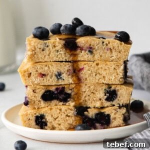 Sheet Pan Pancakes Recipe: Fluffy Oven-Baked Pancake Tray 8 a stack of blueberry pancakes on a plate.