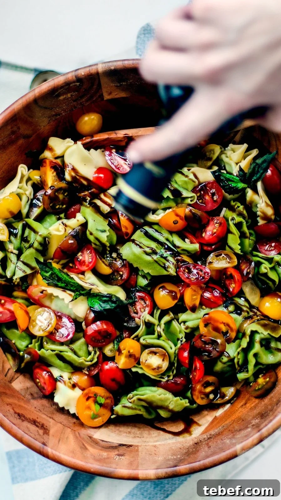 Bruschetta pasta salad being drizzled with balsamic glaze.