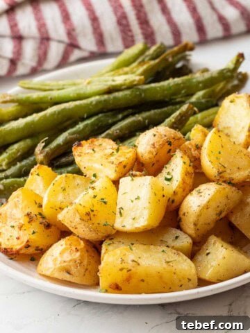 Baked green beans and potatoes on white plate.