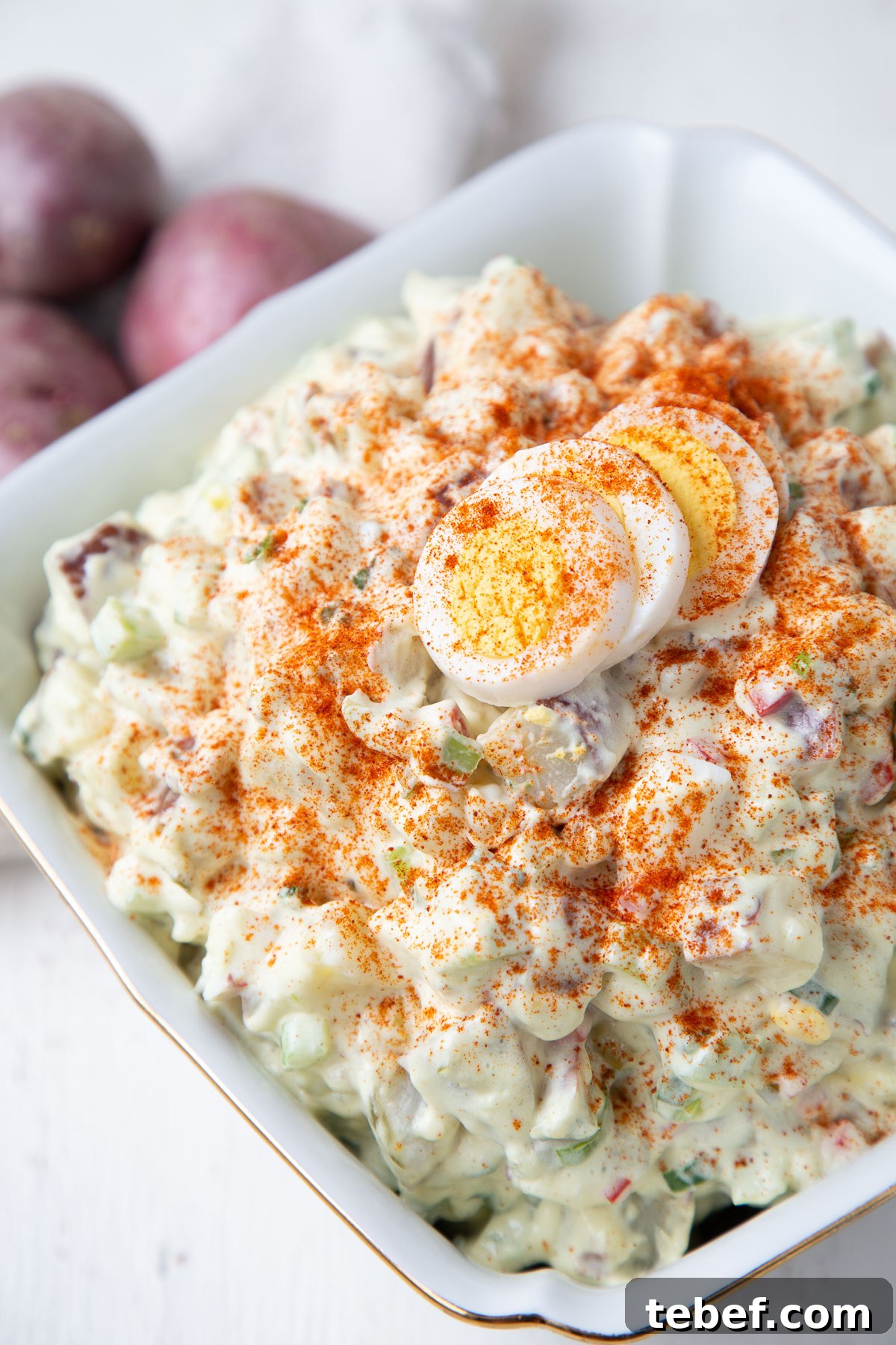 Creamy Red Potato Salad with Tangy Dill Dressing 2 red potato salad topped with hard boiled eggs and paprika.