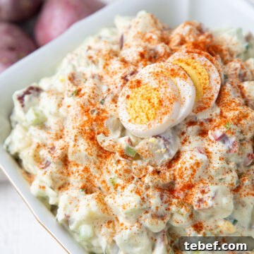 Creamy Red Potato Salad with Tangy Dill Dressing 7 red potato salad topped with hard boiled eggs and paprika in a white dish.