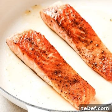 Two salmon fillets in a frying pan.