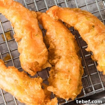 Crispy Beer-Battered Shrimp Recipe — Crunchy Fried Shrimp Guide 13 Golden-brown beer-battered shrimp on a cooling rack.