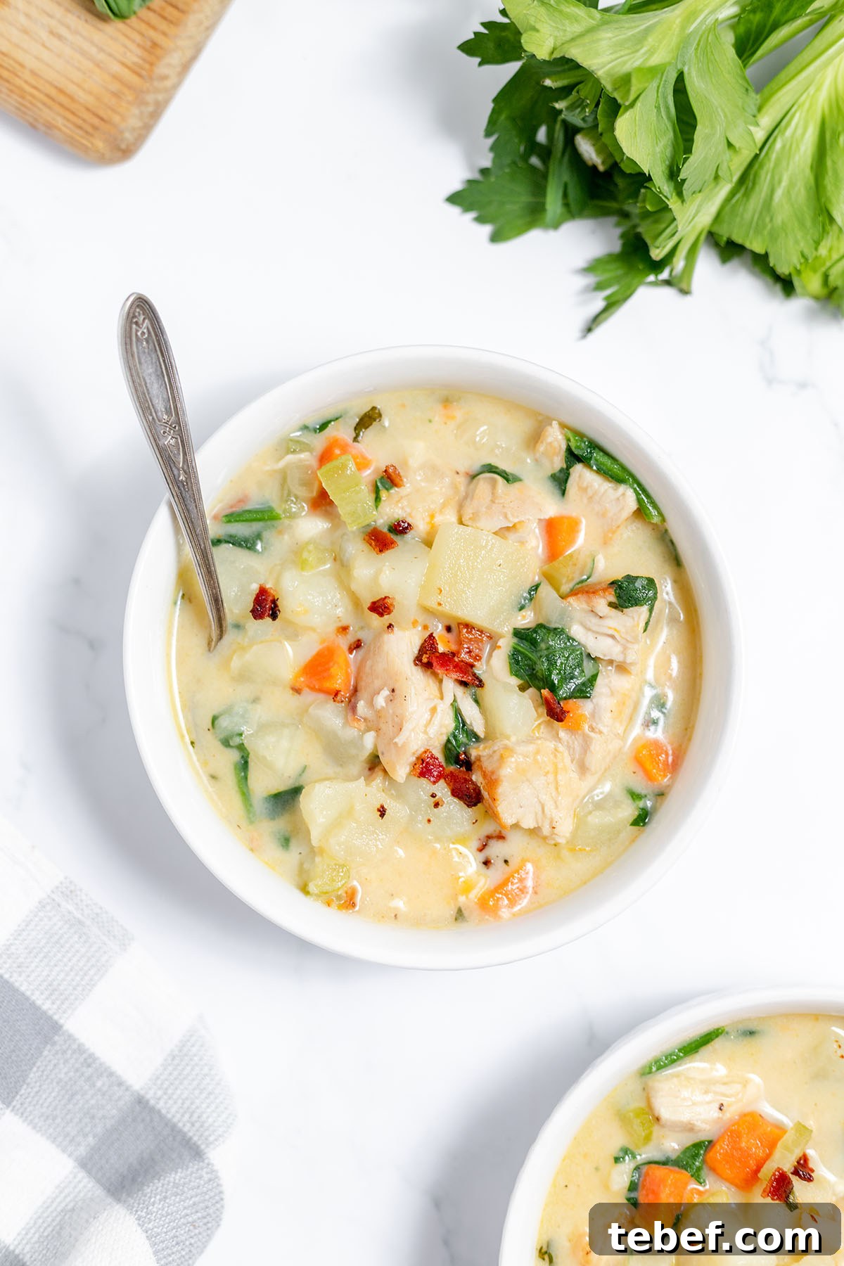 Hearty Chicken and Potato Soup Recipe for Cozy Weeknights 13 Chicken Potato Soup in white bowl with spoon.