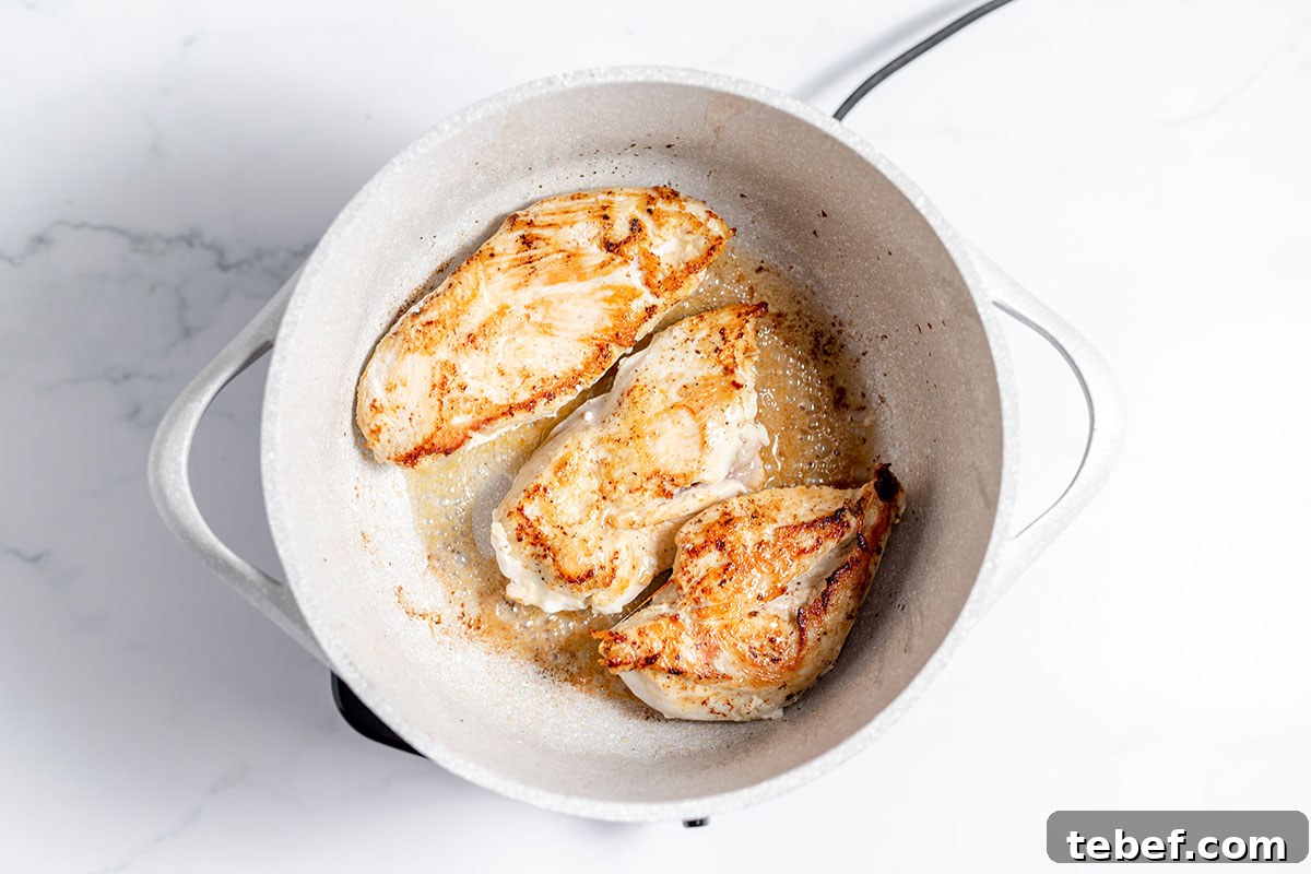 Hearty Chicken and Potato Soup Recipe for Cozy Weeknights 5 Chicken breast cooking in a skillet.