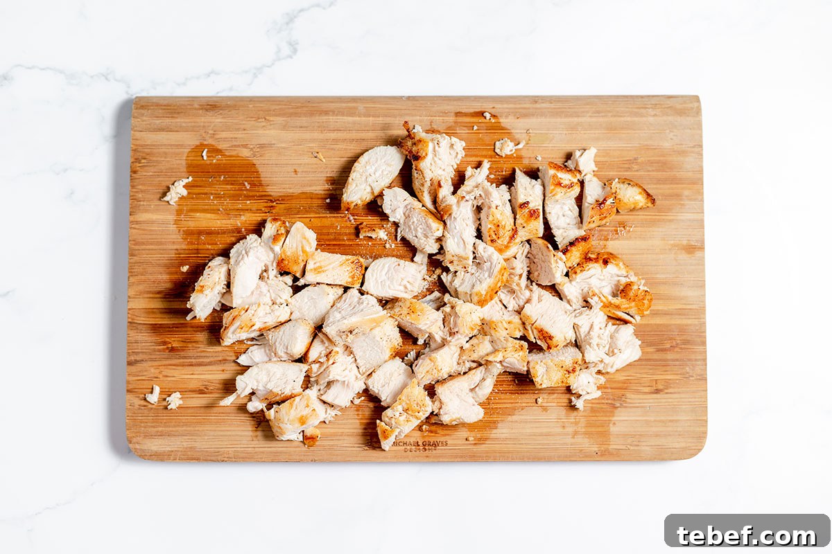 Hearty Chicken and Potato Soup Recipe for Cozy Weeknights 8 Chicken chopped on a wooden cutting board.
