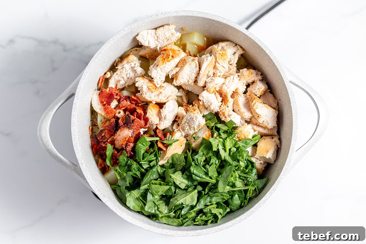Hearty Chicken and Potato Soup Recipe for Cozy Weeknights 9 Spinach, chicken, and bacon are added to the large pot.