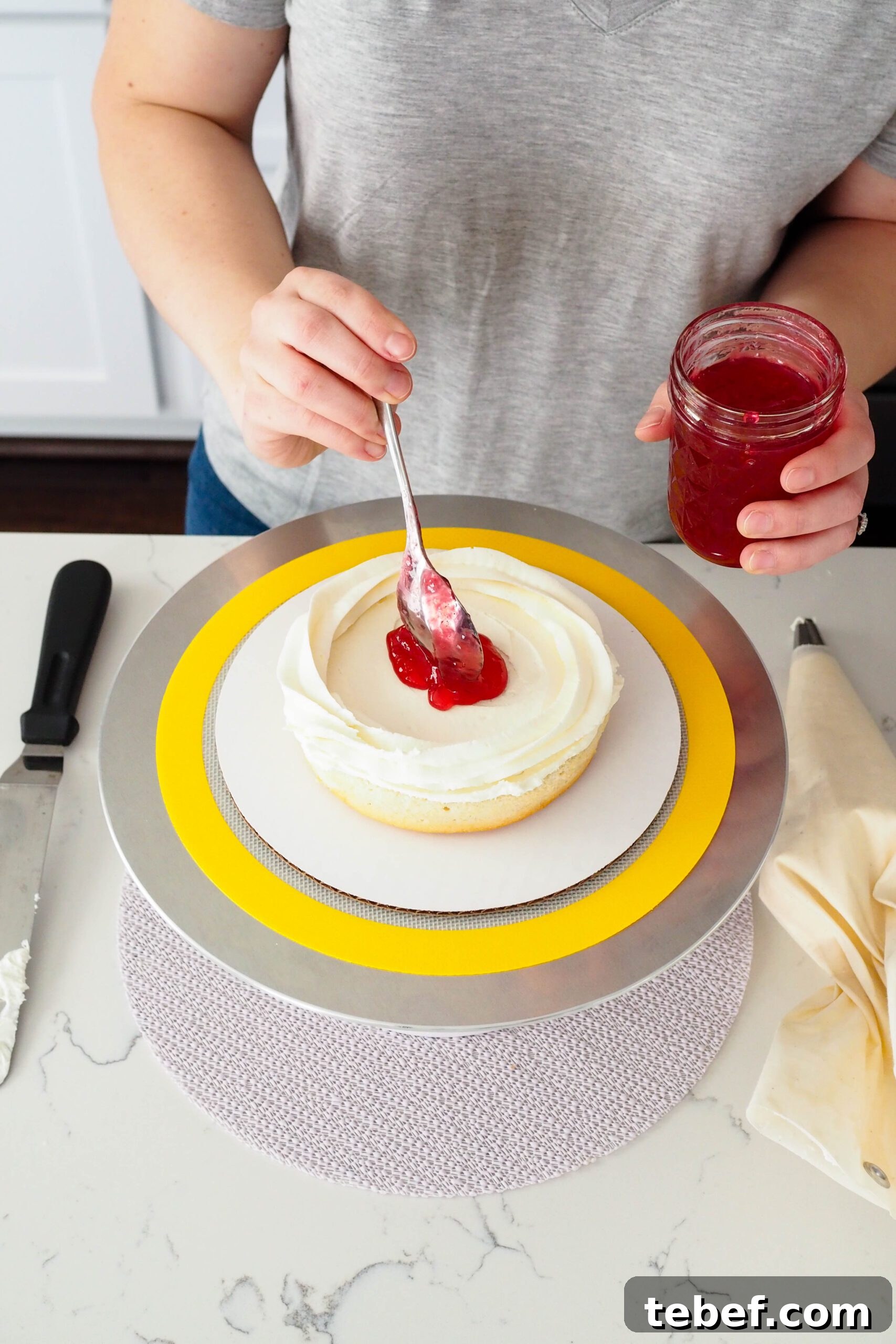 White Chocolate and Pomegranate Layer Cake Recipe 12 Pomegranate jelly is spooned into the center of a white cake layer with a ring of white chocolate buttercream around it.