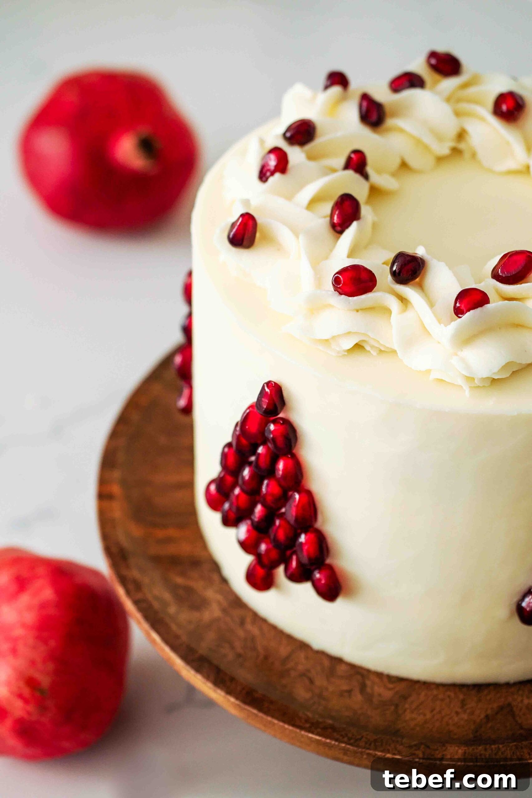 White Chocolate and Pomegranate Layer Cake Recipe 14 A white layer cake decorated with pomegranate seeds in the shape of a Christmas tree.