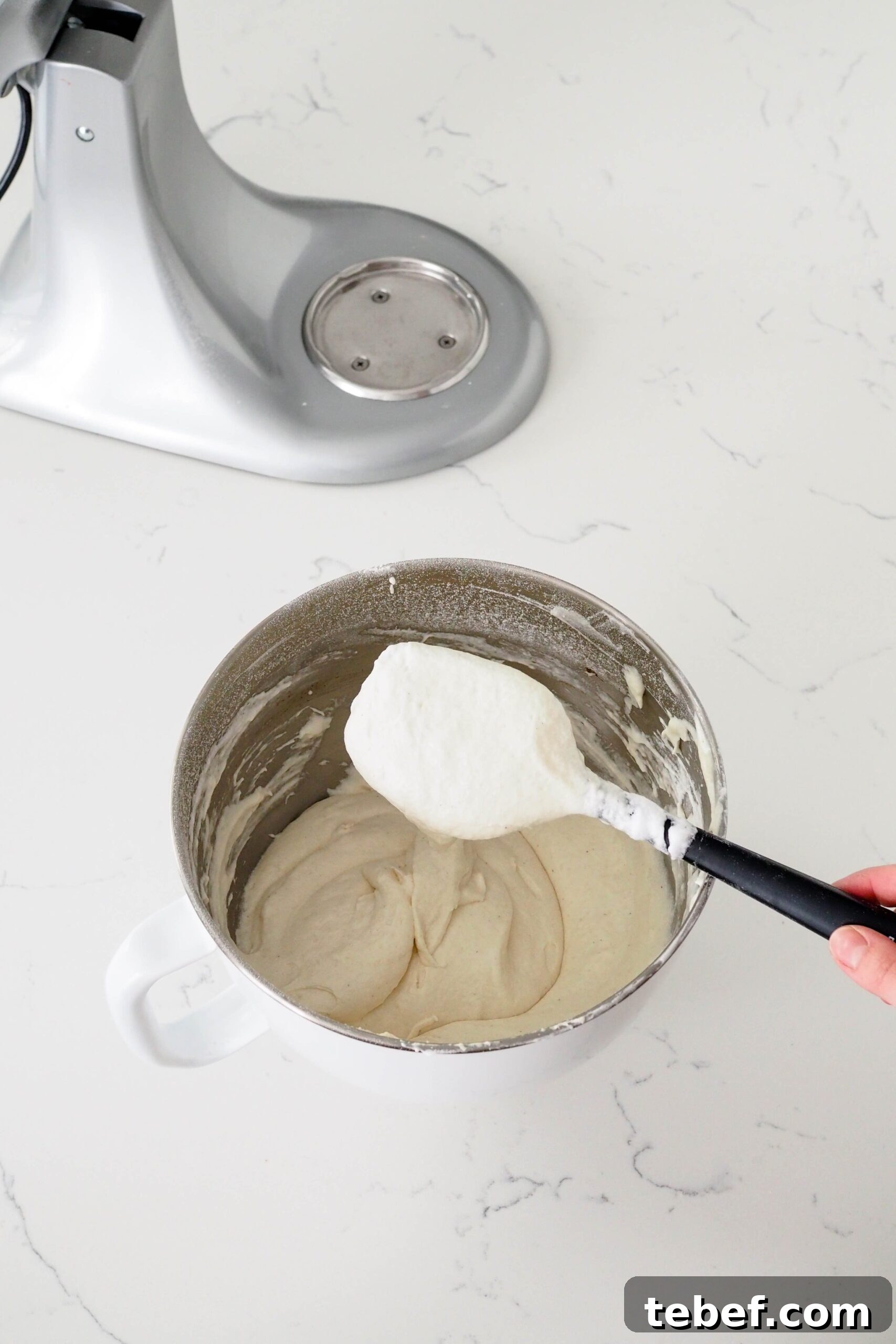 White Chocolate and Pomegranate Layer Cake Recipe 6 A spatula holds up a light batter that contains no streaks.