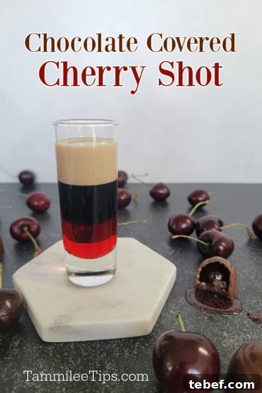 Chocolate covered cherry shot over a layered shot on a white coaster surrounded by chocolate covered cherries