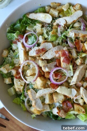 Chicken Caesar Salad with red onion and Caesar dressing.