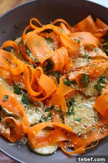 Carrot cucumber salad in bowl with cilantro and sesame seeds.