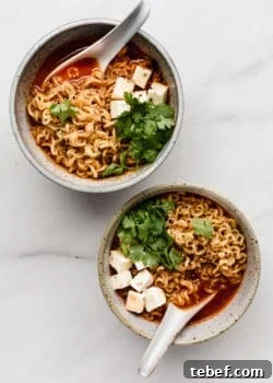 Authentic Kimchi Ramen Recipe: Spicy Korean Noodle Soup Guide 9 two white speckeld ceramic bowls of kimchi ramen with spoons in them
