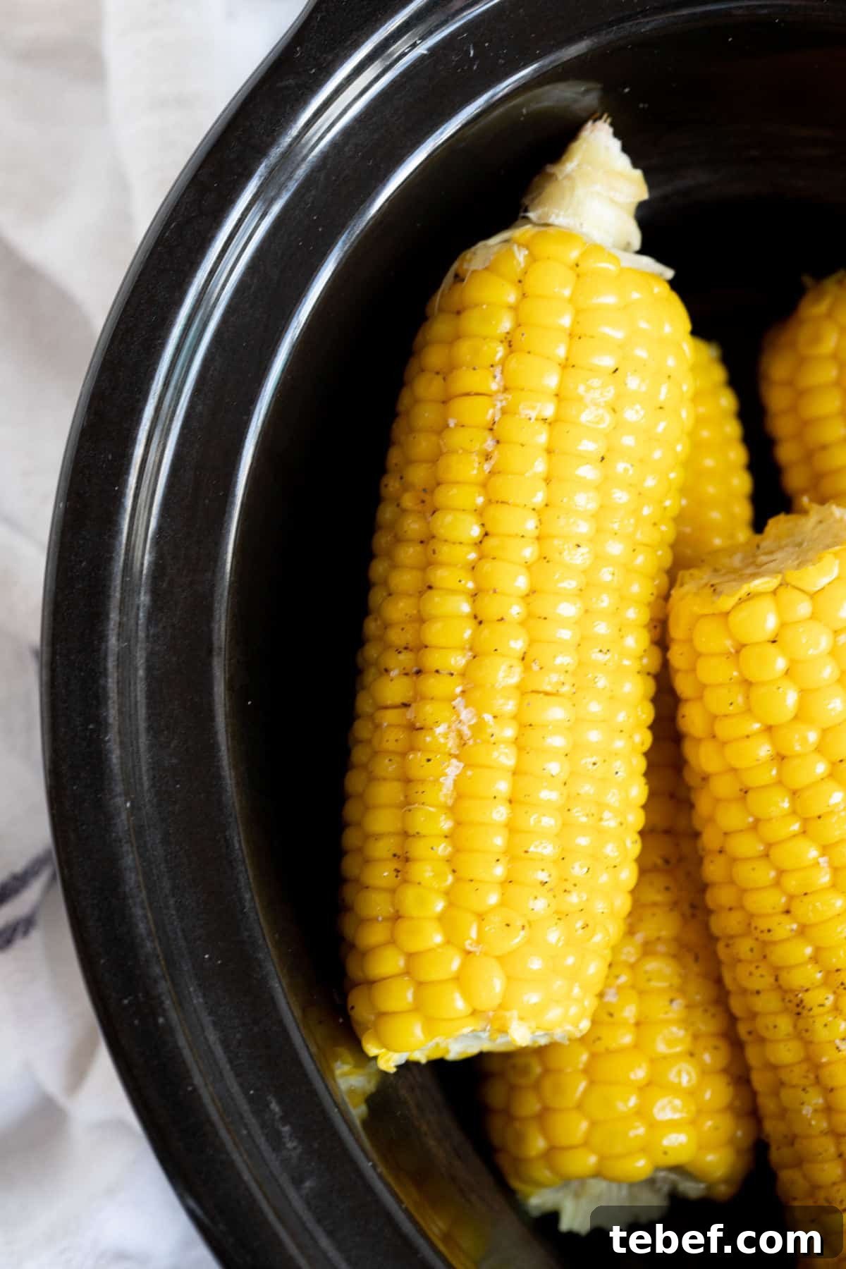 Slow Cooker Corn on the Cob: Tender, Juicy Crockpot Recipe 2 Corn in a black slow cooker.