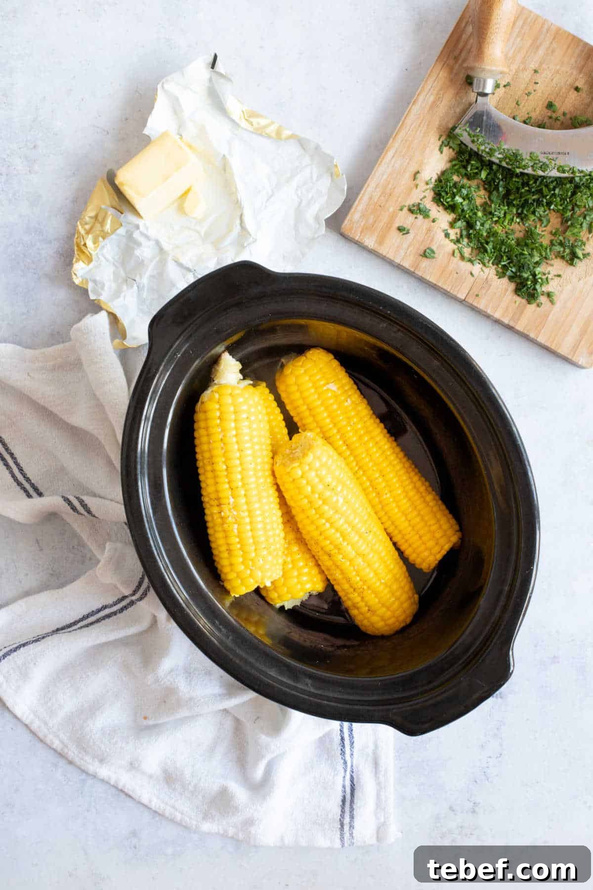 Slow Cooker Corn on the Cob: Tender, Juicy Crockpot Recipe 4 Corn on the cob in the slow cooker with butter and parsley.