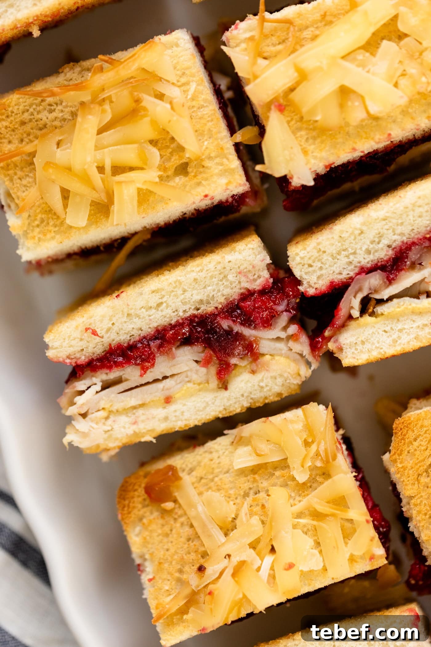 Turkey and Cranberry Croque Monsieur Recipe for Holiday Sandwiches 2 Turkey cranberry croque monsieur sitting on white plate with linen napkin underneath all on white surface